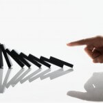 Businessman Touching Domino Pieces Arranged in a Line